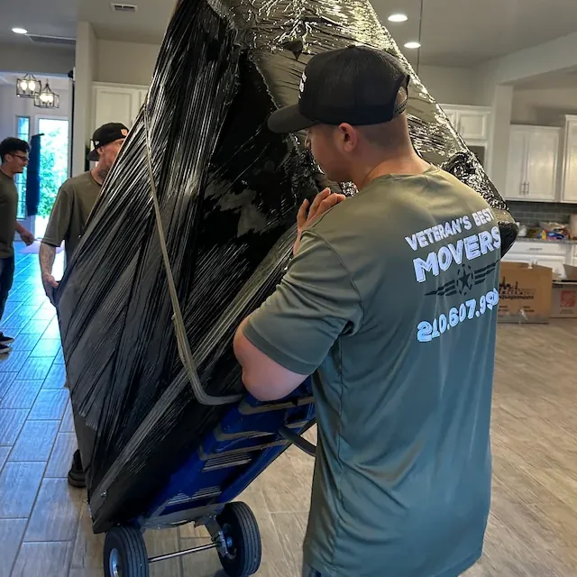 Veterans Best Movers crew moving a wrapped couch on a dolly